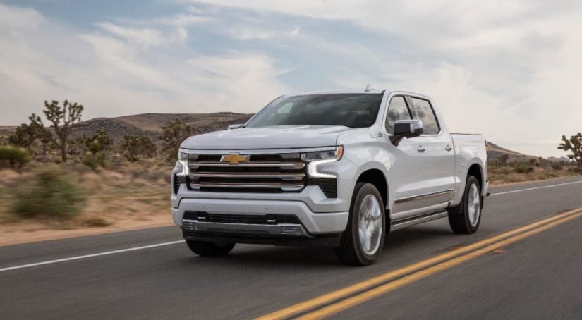 A white 2022 Chevy Silverado 1500 High Country is shown from the front at an angle during a 2022 Chevy Silverado 1500 vs 2022 Ram 1500 comparison.