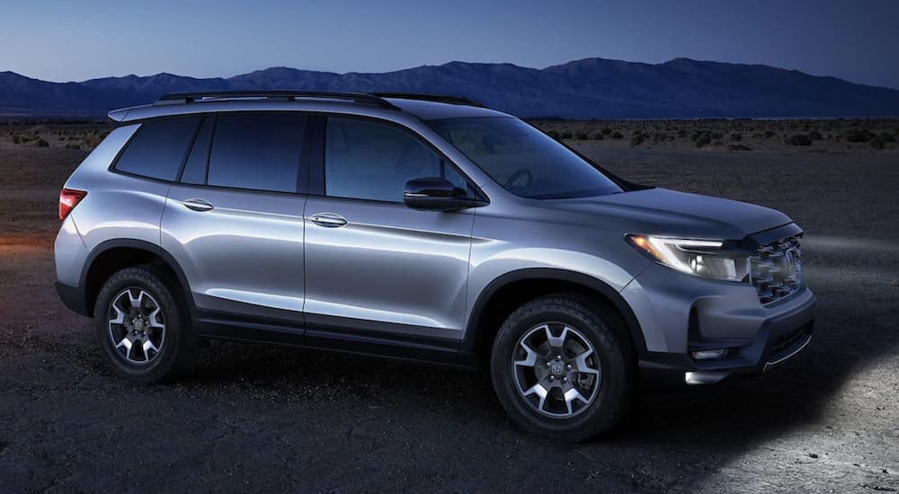 A silver 2022 Honda Passport TrailSport is shown parked in the mountains at dusk.