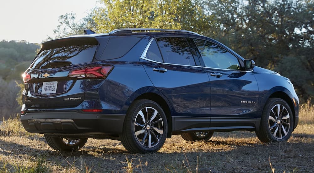 A blue 2022 Chevy Equinox is shown from the side parked in a field during a 2022 Chevy Equinox vs 2022 Honda CR-V comparison.