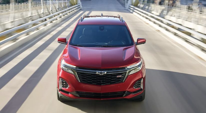 A red 2022 Chevy Equinox is shown from the front driving on an open road during a 2022 Chevy Equinox vs 2022 Honda CR-V comparison.