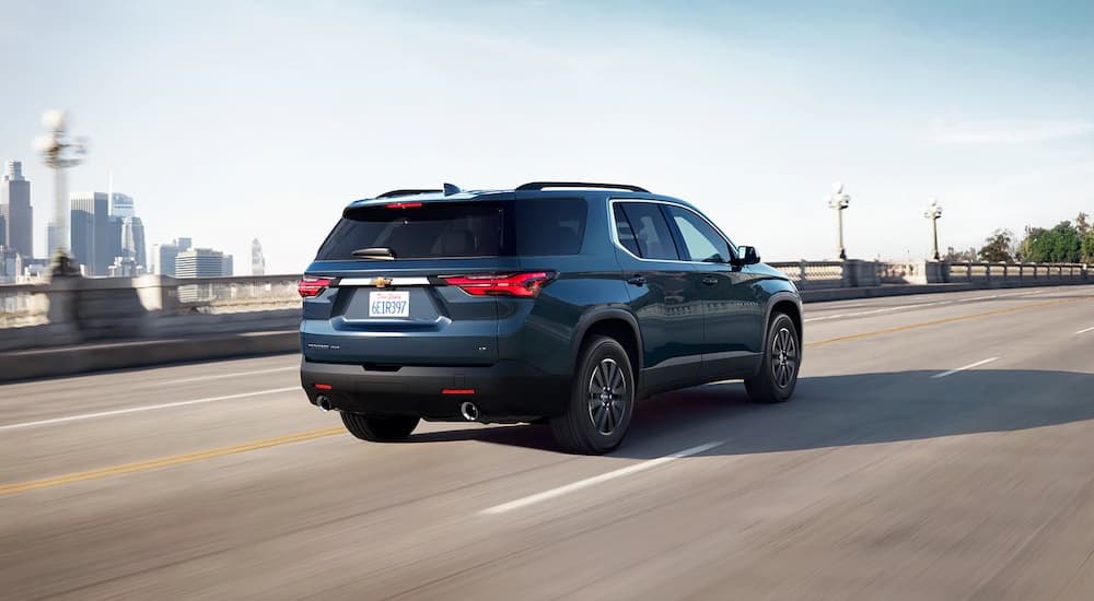 A blue 2022 Chevy Traverse is shown from the rear driving down an open highway.