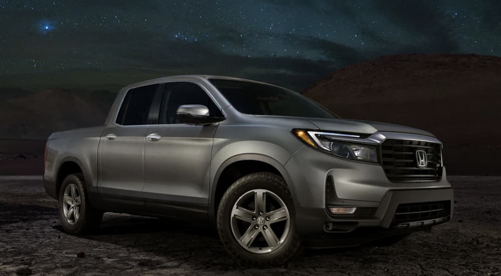 A grey 2022 Honda Ridgeline RTL-E is shown from the side parked in a desert at night.