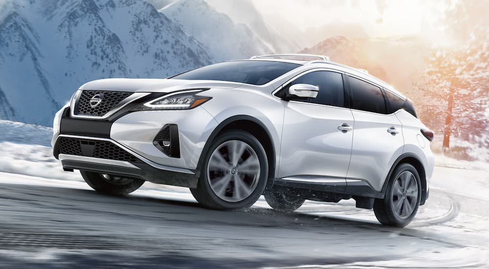 A white 2022 Nissan Murano is shown from the side driving on a snowy road.
