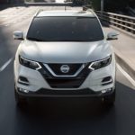 A white 2022 Nissan Rogue Sport is shown from the front driving on an open road.