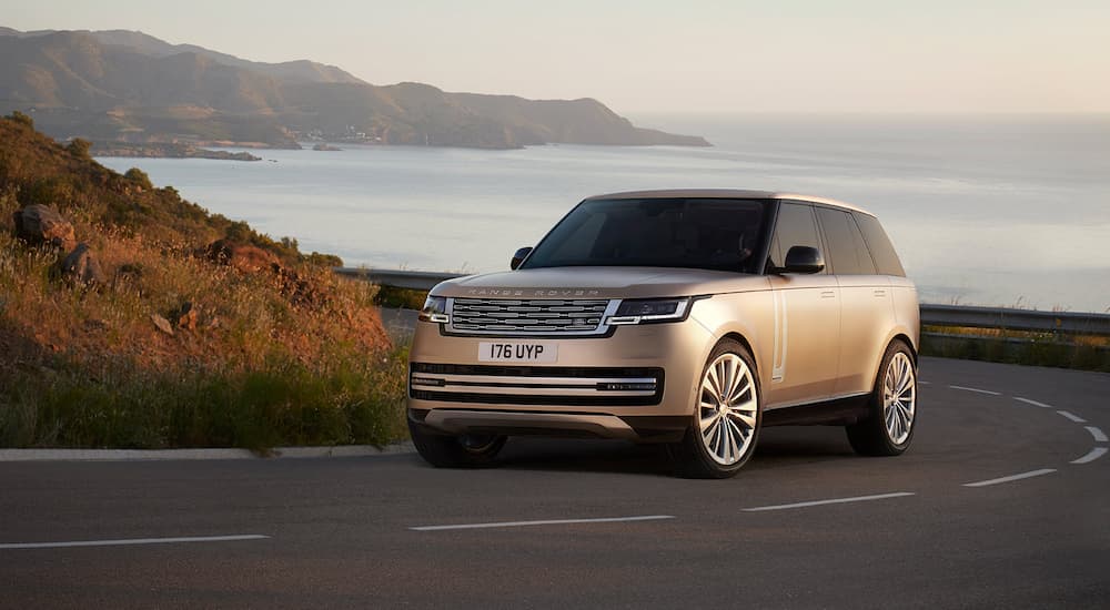 A gold 2022 Range Rover SV is shown driving on a winding road.