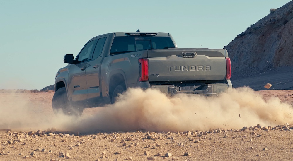 A grey 2022 Toyota Tundra is shown from the rear while kicking up dust off-road.