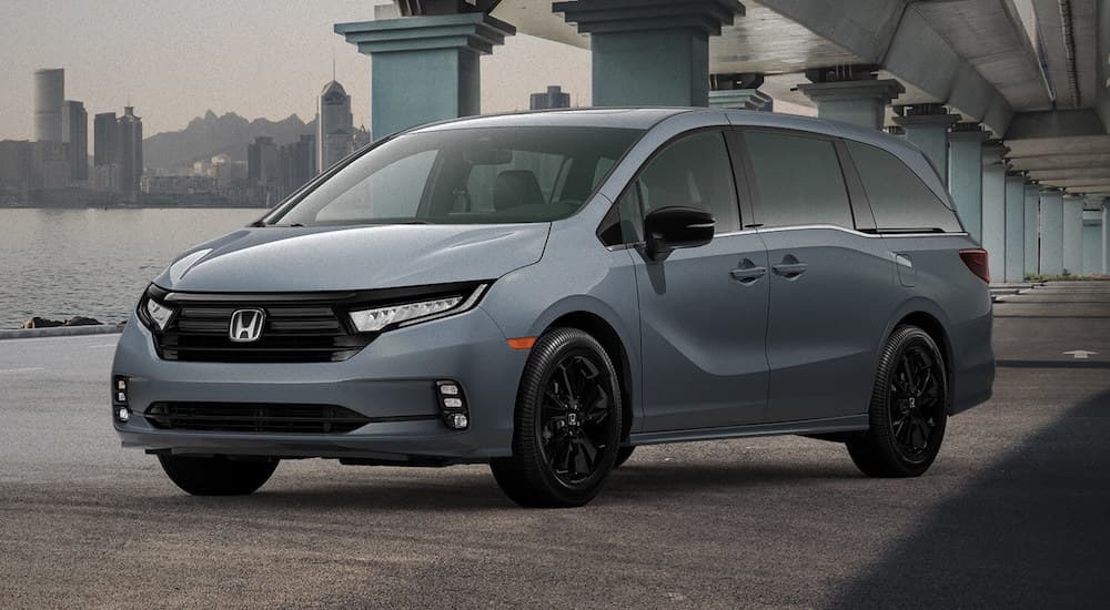 A greay 2023 Honda Odyssey Sport is shown parked near a bay and a city.