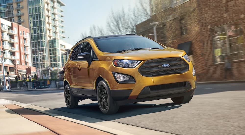 A yellow 2022 Ford EcoSport is shown driving on a city street.