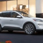A white 2022 Ford Escape is shown parked in front of a shop after visiting a Ford dealer.