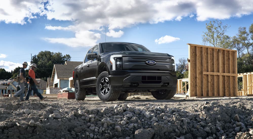 A black 2022 Ford F-150 Lightning Pro is shown near an unfinished house.