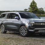 A silver 2022 Chevy Suburban Z71 is shown parked on a lakeside during a 2022 Chevy Suburban vs 2022 Ford Expedition comparison.