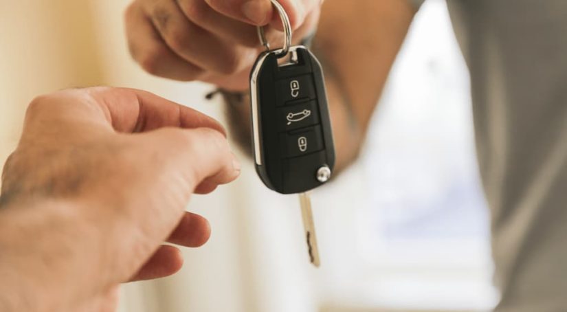 A person is shown handing over a car key.