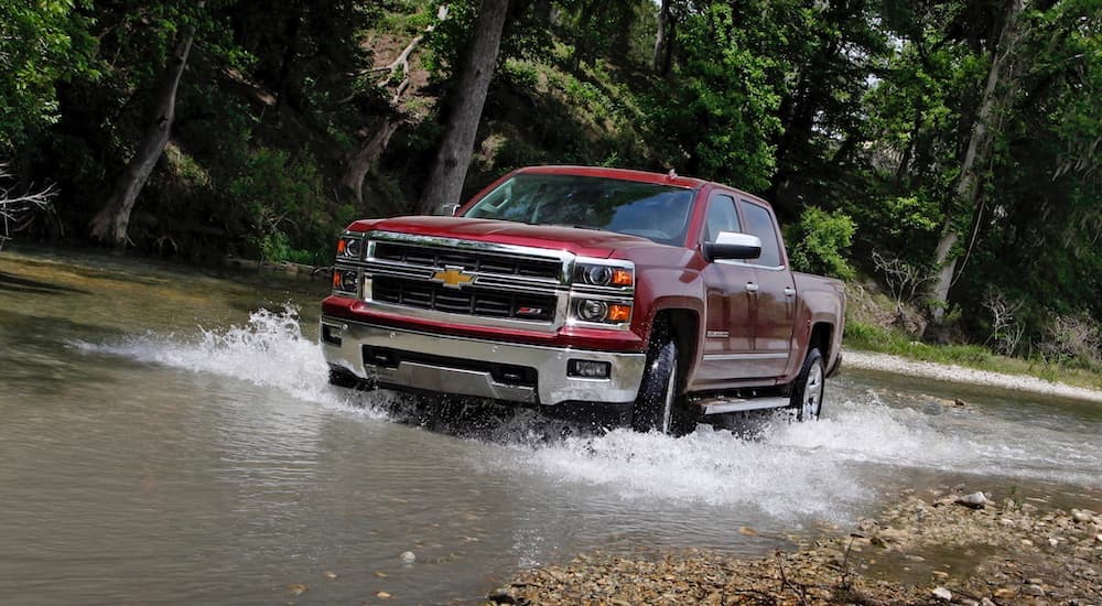 A red 2017 Chevy Silverado 1500 is shown from the front while driving through water.