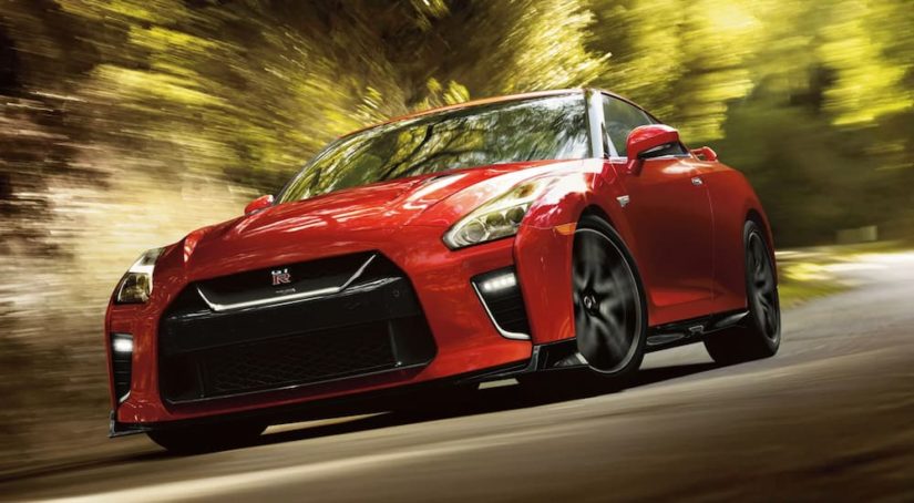 A red 2021 Nissan GT-R is shown speeding down a road after leaving a Nissan dealer.