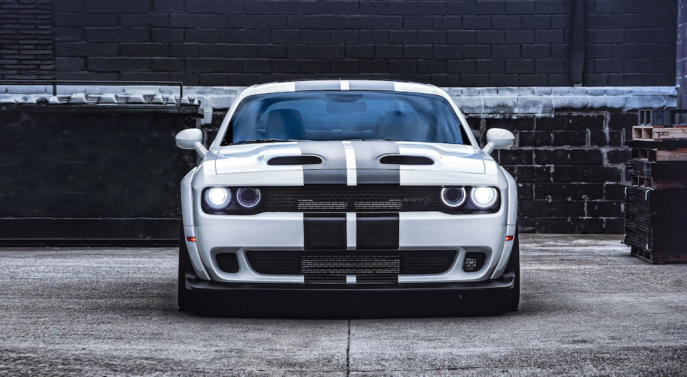 A white and black striped 2022 Dodge Challenger is shown from the front parked near a brick wall.