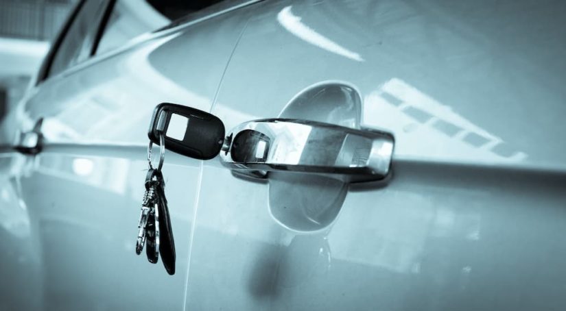 A set of keys are shown in the lock of a silver vehicle after someone went through the 'sell my car' process.