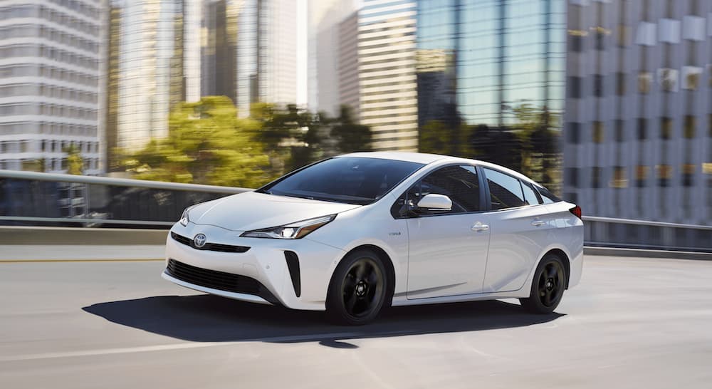 A white 2020 Toyota Prius is shown from the side while driving through a city.