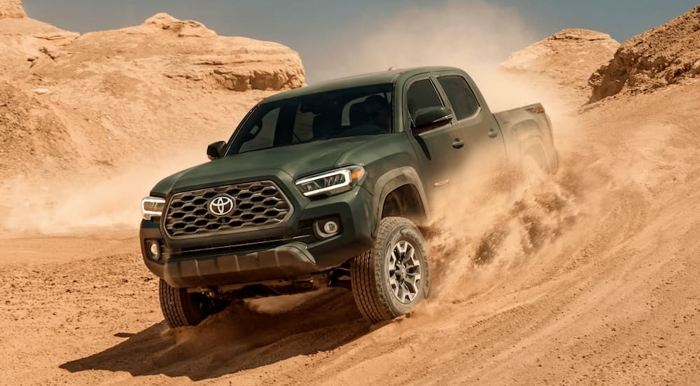 A green 2020 Toyota Tacoma is shown from the front while driving through a sand dune.