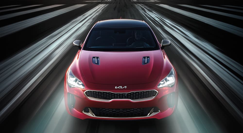 A red 2021 Kia Stinger is shown driving on an airstrip at night.