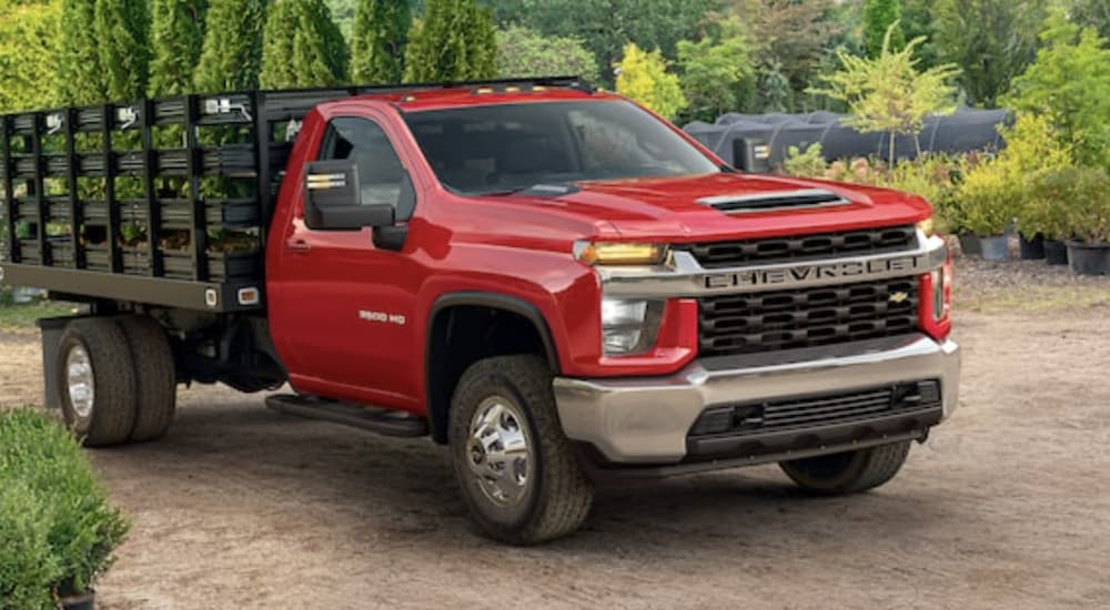 A red 2022 Chevy Silverado 3500 Chassis Cab is shown parked at a plant nursery.