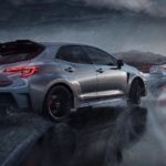 A grey 2023 Toyota GR Corolla is shown from the rear while taking a corner in the rain.
