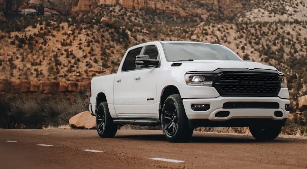 A white 2022 Ram 1500 is shown from the front at an angle on a desert road.