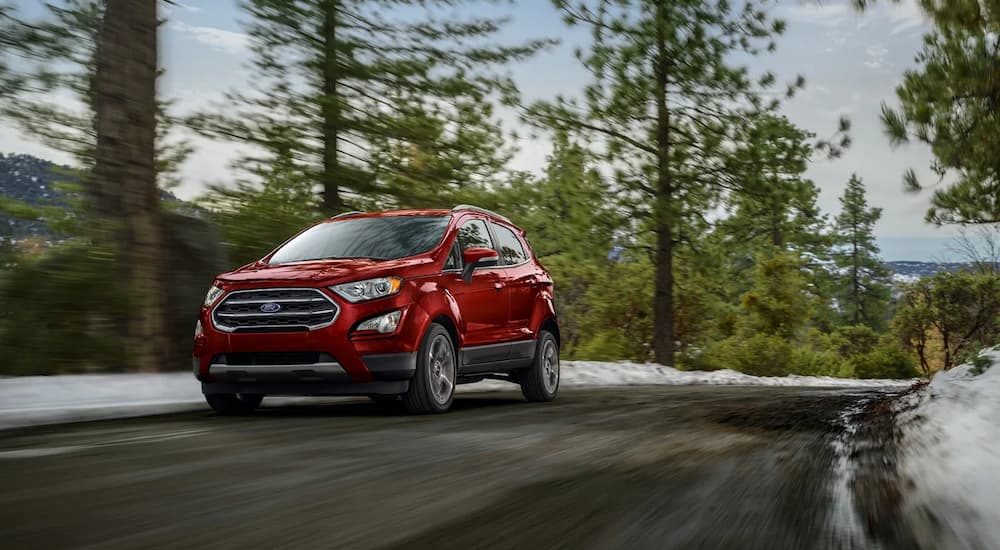 A red 2021 Ford EcoSport is shown driving on a forest road.