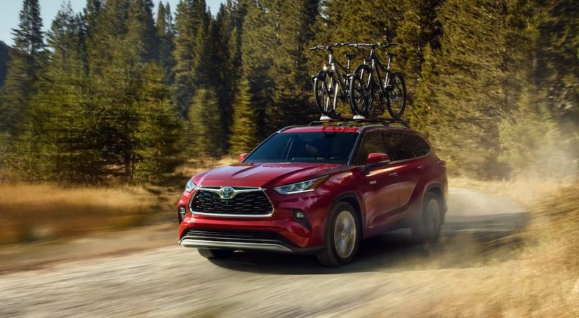 A red 2022 Toyota Highlander Hybrid is shown from the front on a dirt trail while loaded with bikes.
