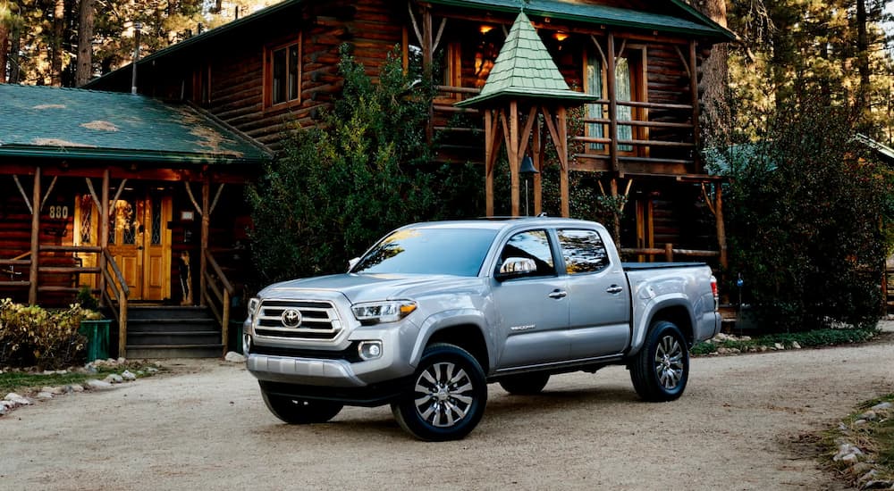 A silver 2022 Toyota Tacoma Limited is shown parked outside of a log cabin.