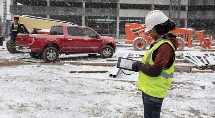 A red 2022 Ford F-150 XLT is shown at a job site during a snowstorm.