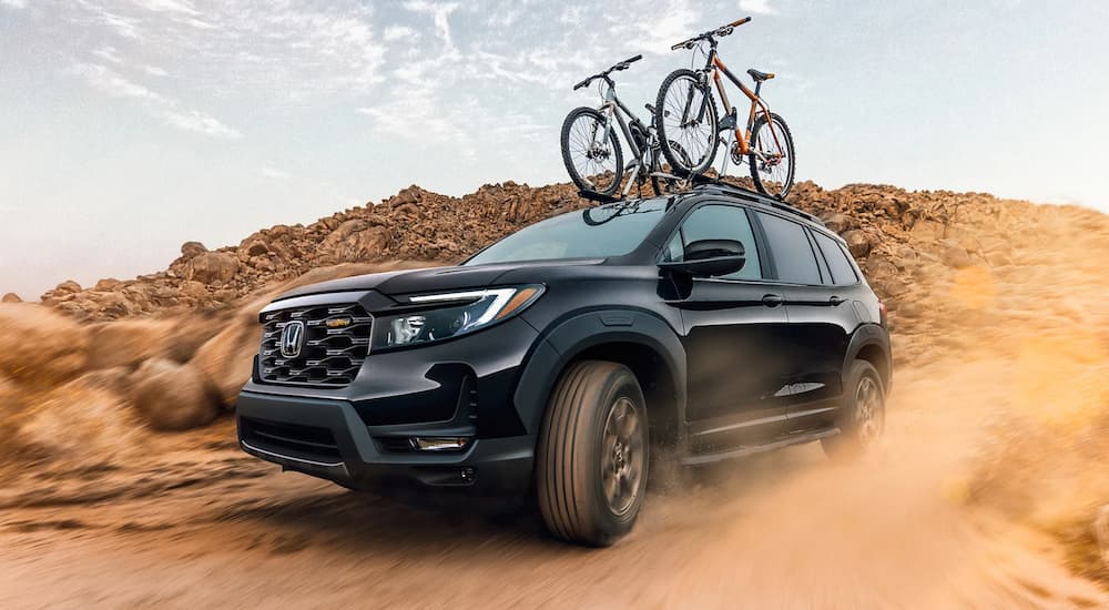 A black 2022 Honda Passport Trailsport is shown from the front at an angle while driving in the sand.