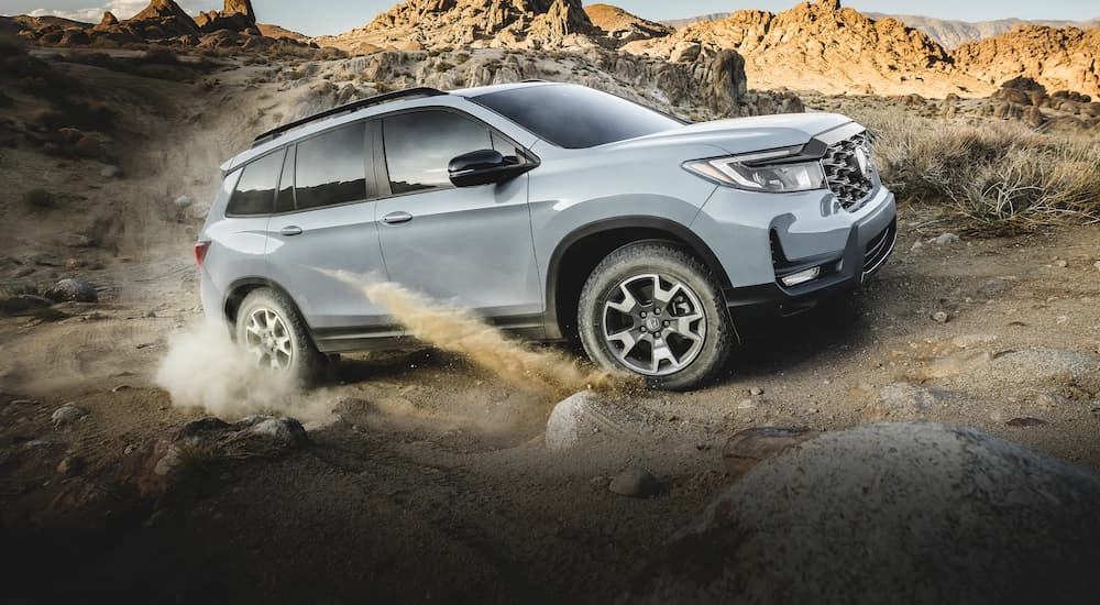 A grey 2022 Honda Passport Trailsport is shown from the side while driving off-road.