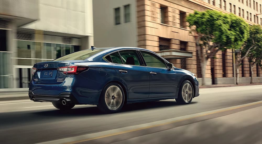A blue 2022 Subaru Legacy Touring XT is shown driving on a city street.