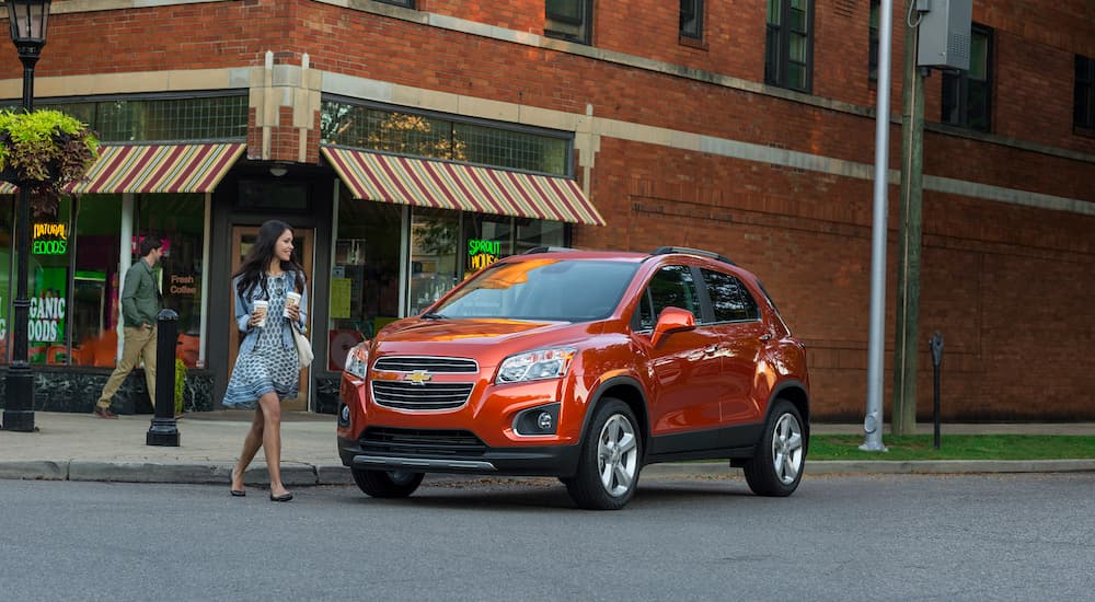 An orange 2016 Chevy Trax is shown parked in front of a shop.