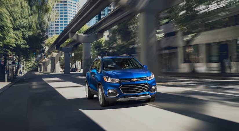 A blue 2022 Chevy Trax is shown driving on a city street after leaving a Chevrolet dealer.