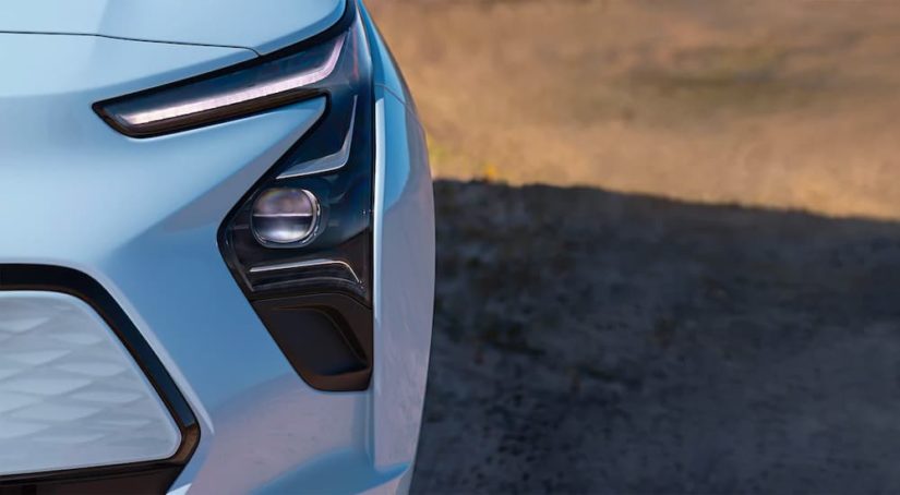 A close up shows the driver side headlight and fog light on a pale blue 2022 Chevy Bolt EV.