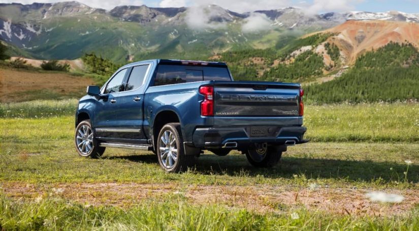 A blue 2022 Chevy Silverado High Country is shown from the rear while parked in an open field.
