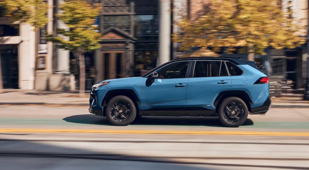 A blue 2022 Toyota RAV4 Hybrid XSE is shown from the side driving on a city street.