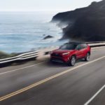 A red 2022 Toyota RAV4 Prime XSE is shown driving on a coastal road.