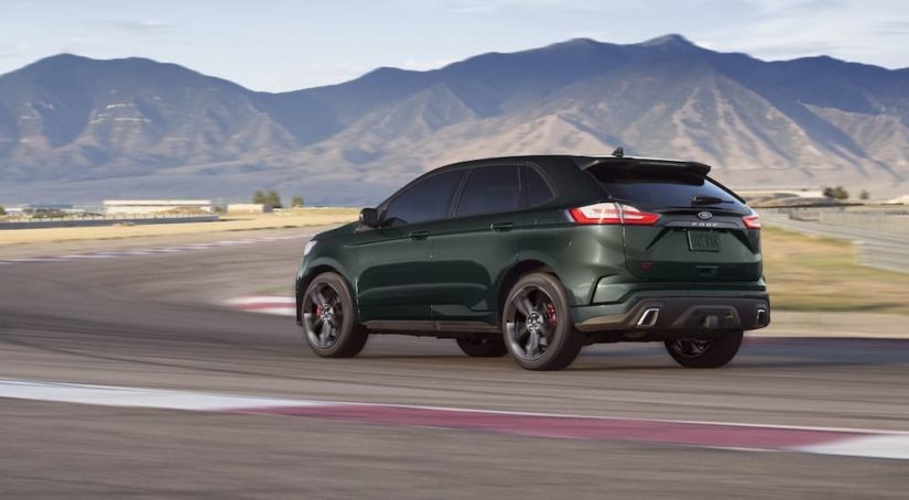 A dark green 2022 Ford Edge ST is shown driving on a racetrack after leaving a Ford dealership.