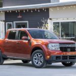 An orange 2022 Ford Maverick is shown from the front parked in a driveway after leaving a Ford dealer.