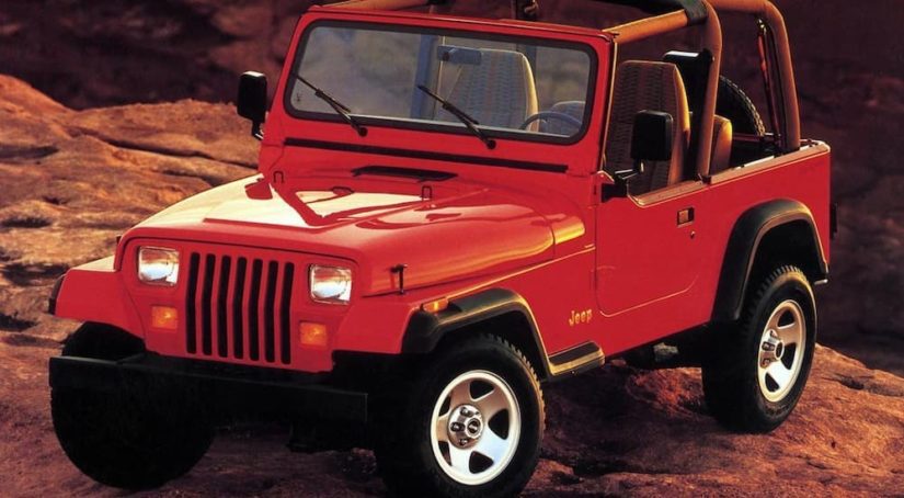 A red 1980s Jeep Wrangler YJ is shown after leaving a Jeep dealer.