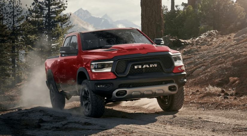 A red 2022 Ram 1500 Rebel is shown driving on a dirt road for a Ram buyers guide.
