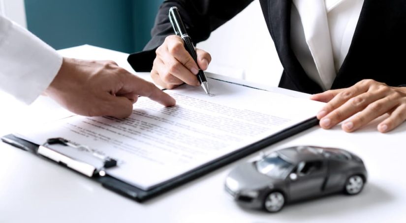 A person is shown doing paperwork for bad credit car loans at a car dealership.