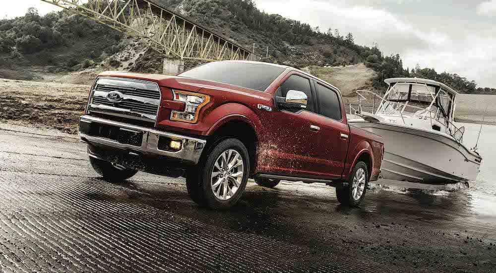 A red 2018 Ford F-150 is shown from the front at an angle while pulling a boat out of a boat ramp.