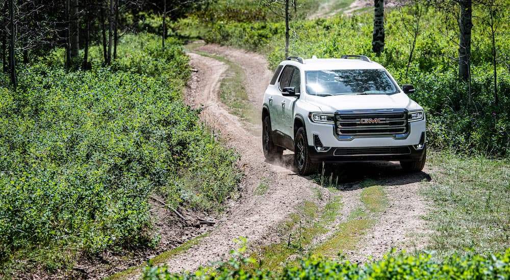 A white 2023 GMC Acadia AT4 is shown from the front on a trail.