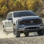 A 2021 Ford F-150 Tremor is shown from the front while driving off-road after leaving a Ford dealer.