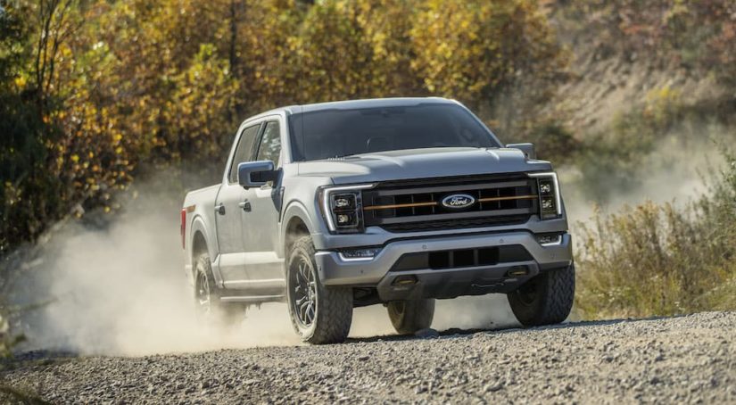 A 2021 Ford F-150 Tremor is shown from the front while driving off-road after leaving a Ford dealer.