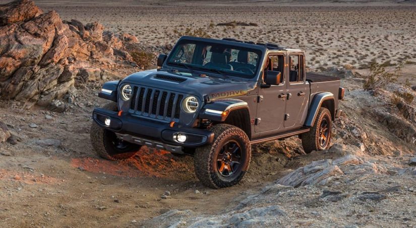 A grey 2022 Jeep Gladiator Mojave is shown driving off-road during a 2022 Jeep Gladiator vs 2022 Toyota Tacoma comparison.