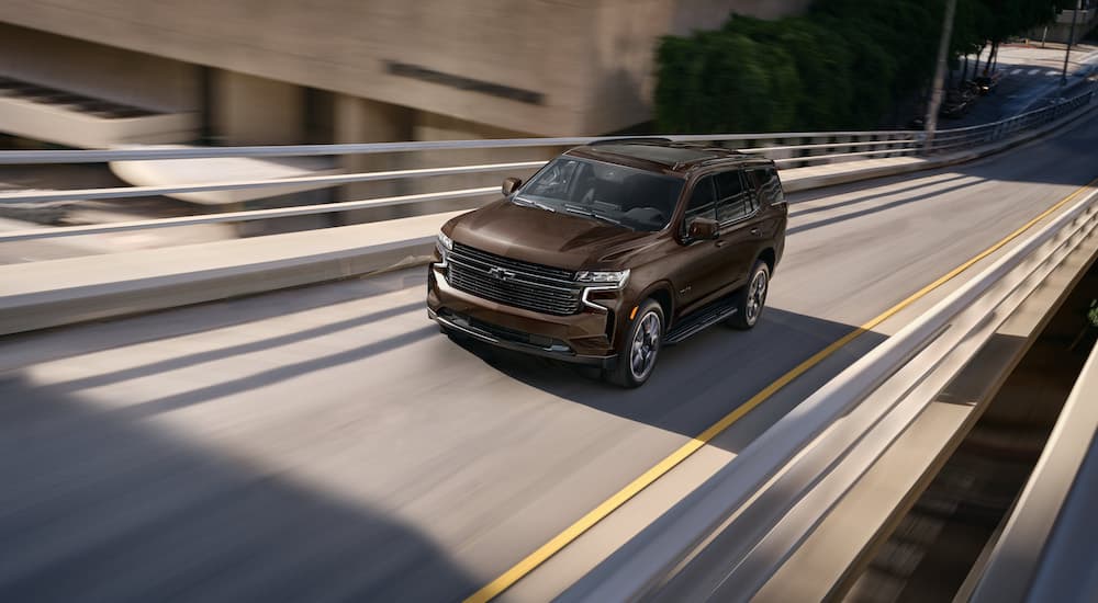 A brown 2023 Chevy Tahoe is shown while driving on an on-ramp.